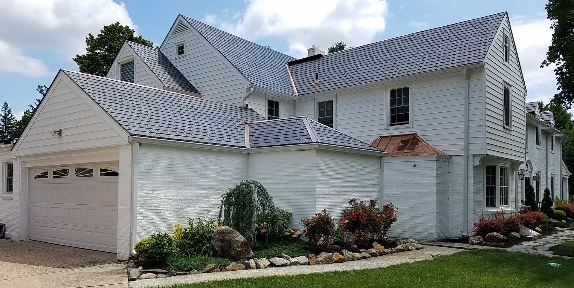 A large white house with a blue roof and a garage.