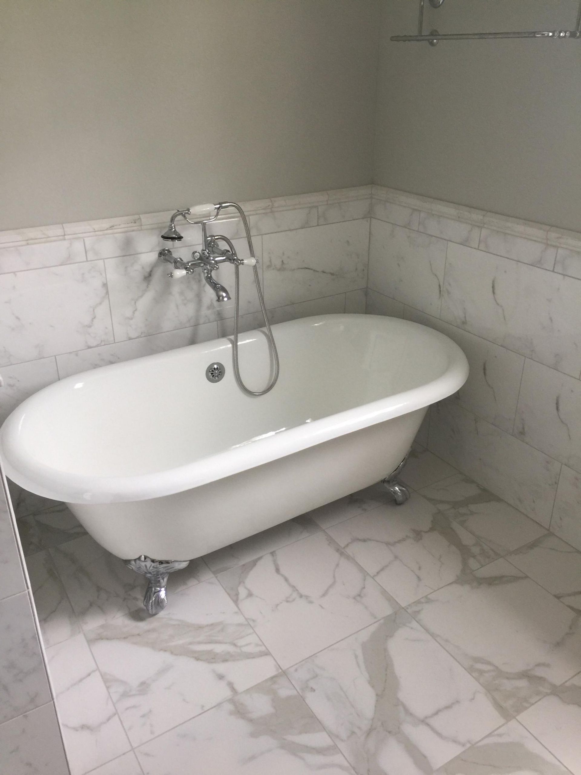 A white bathtub with claw feet is in a bathroom.
