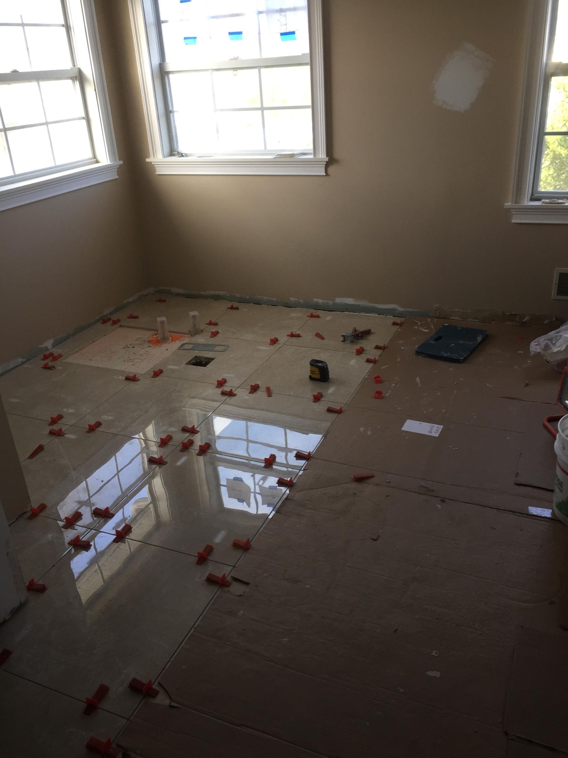 A room with a lot of tiles on the floor and a window.