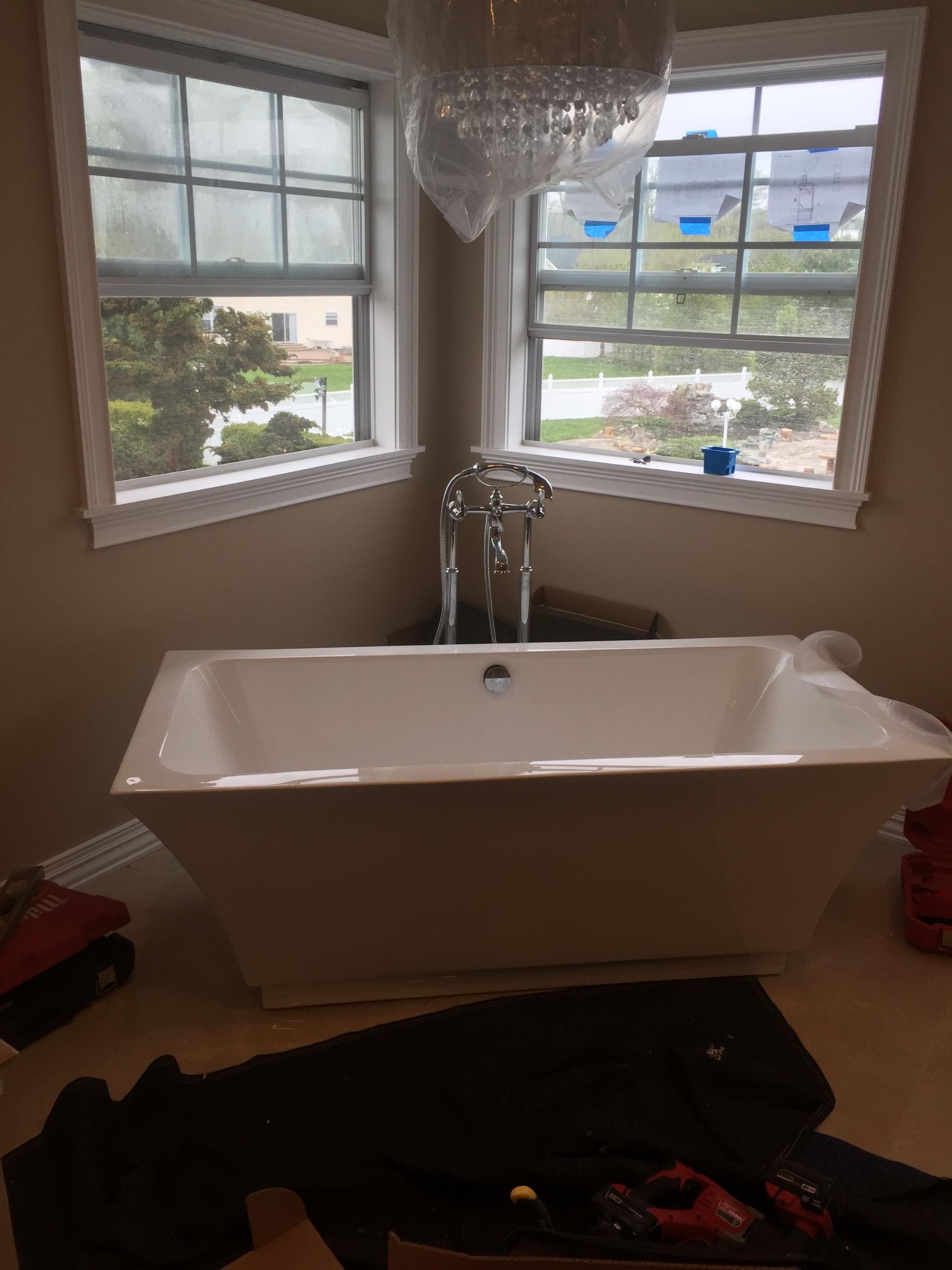 A white bathtub is sitting in a bathroom next to a window.