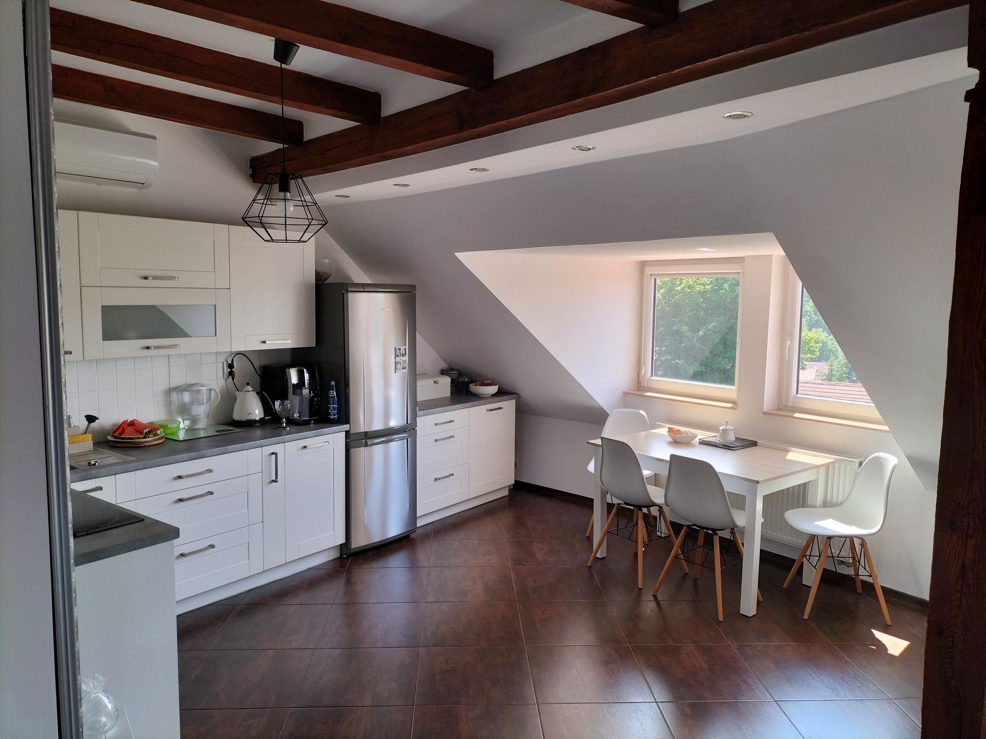 A kitchen with white cabinets , a refrigerator , a table and chairs.