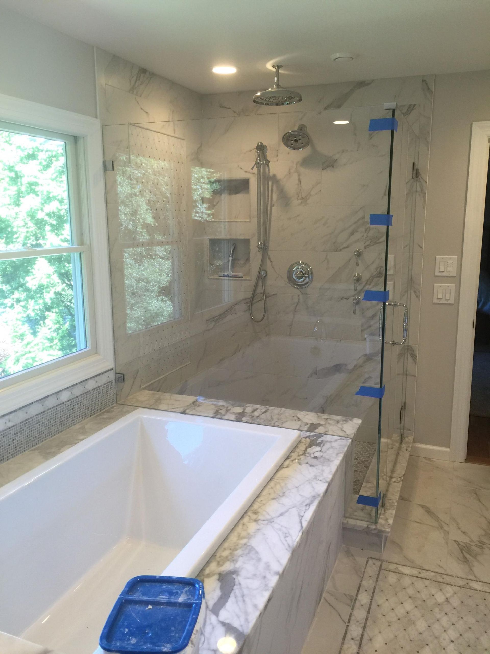A bathroom with a tub , shower , and window.