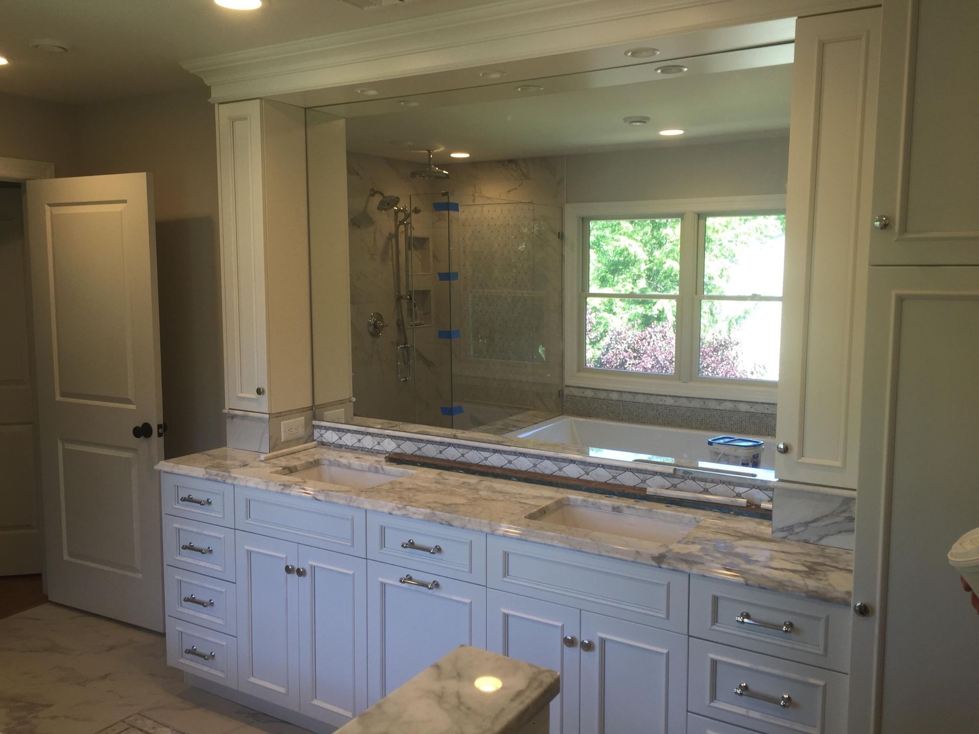 A bathroom with a large mirror over the sink and a tub.