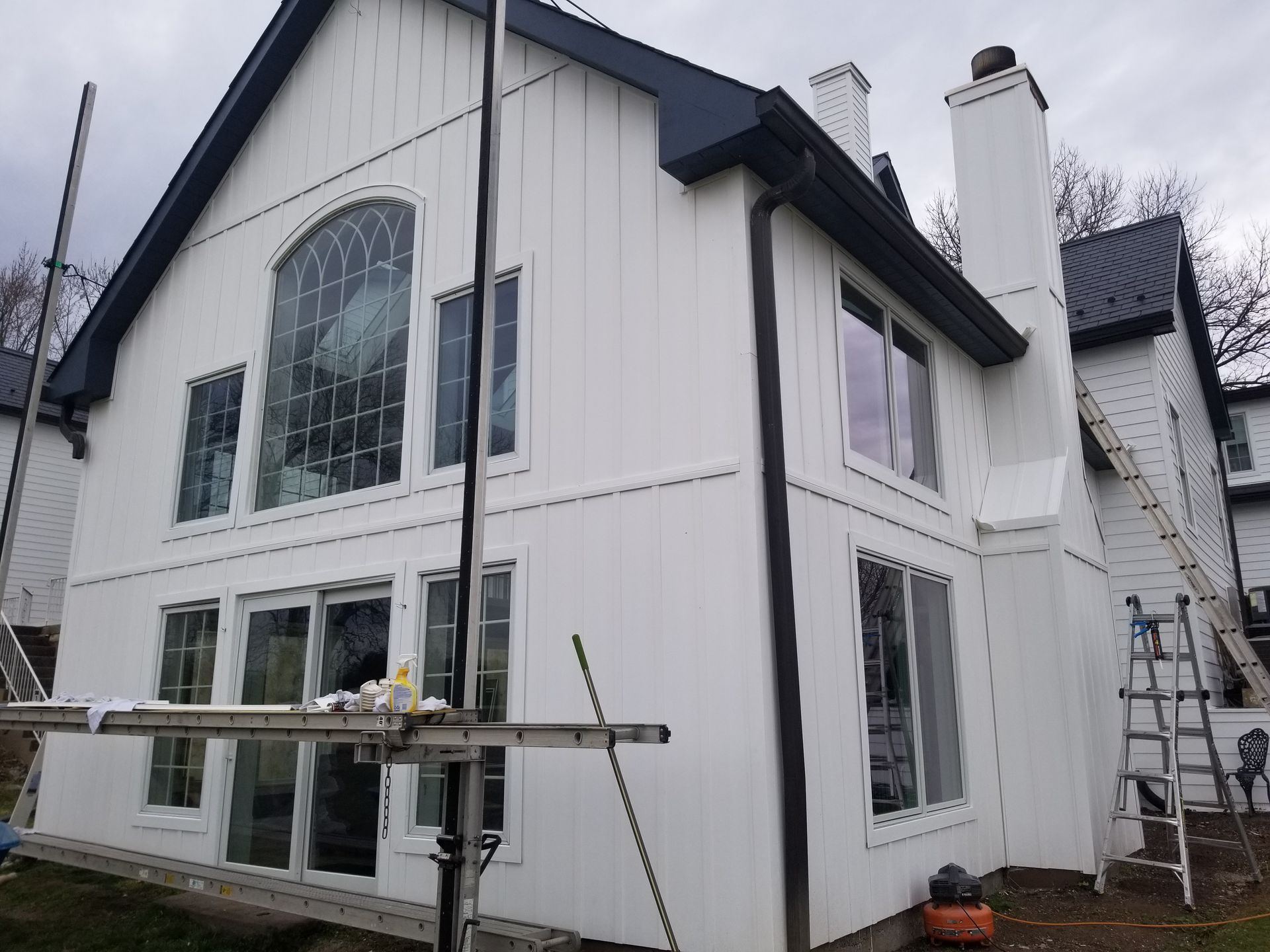 A large white house with a black roof is being painted.