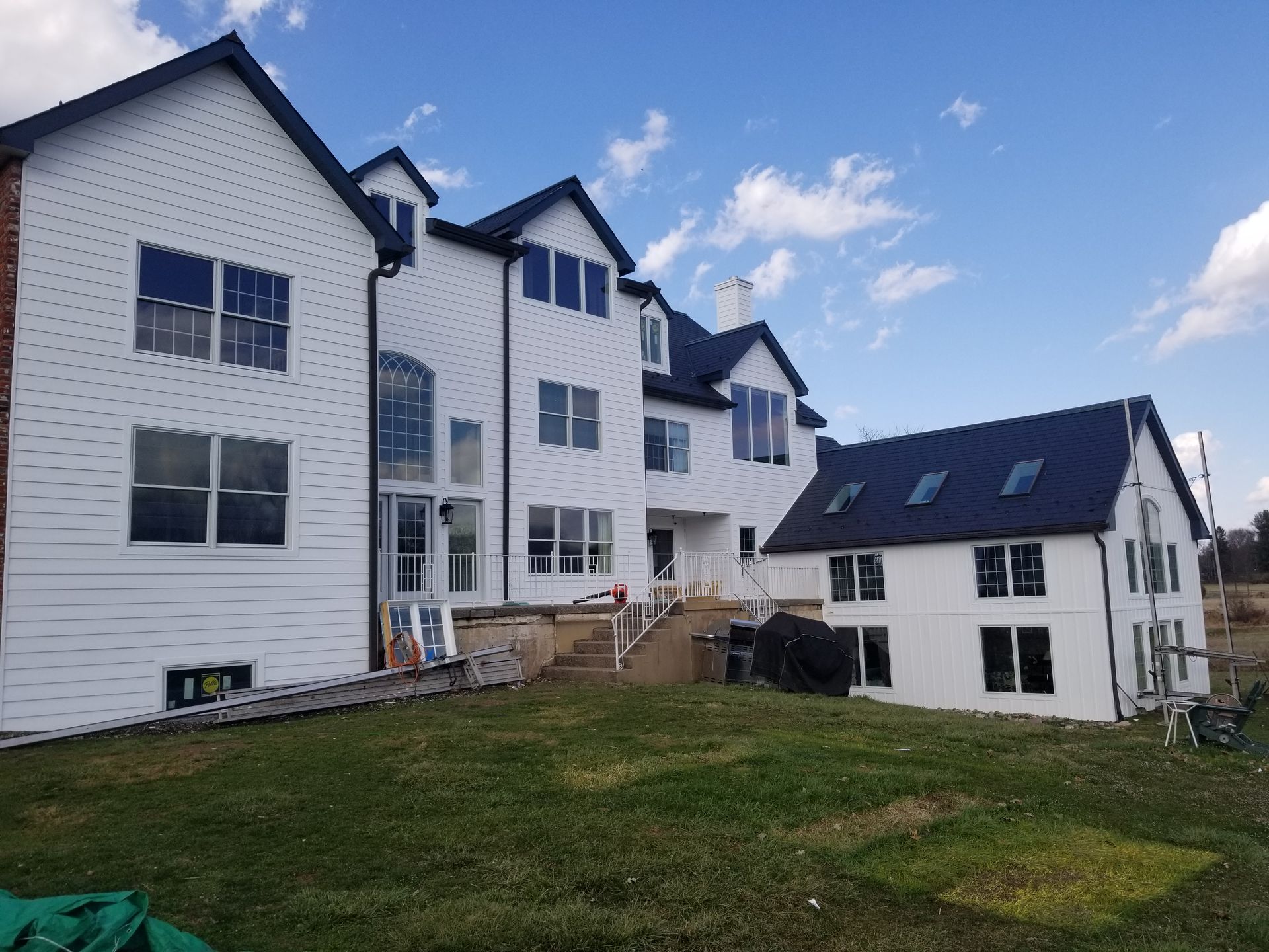 A large white house with a black roof is being built.