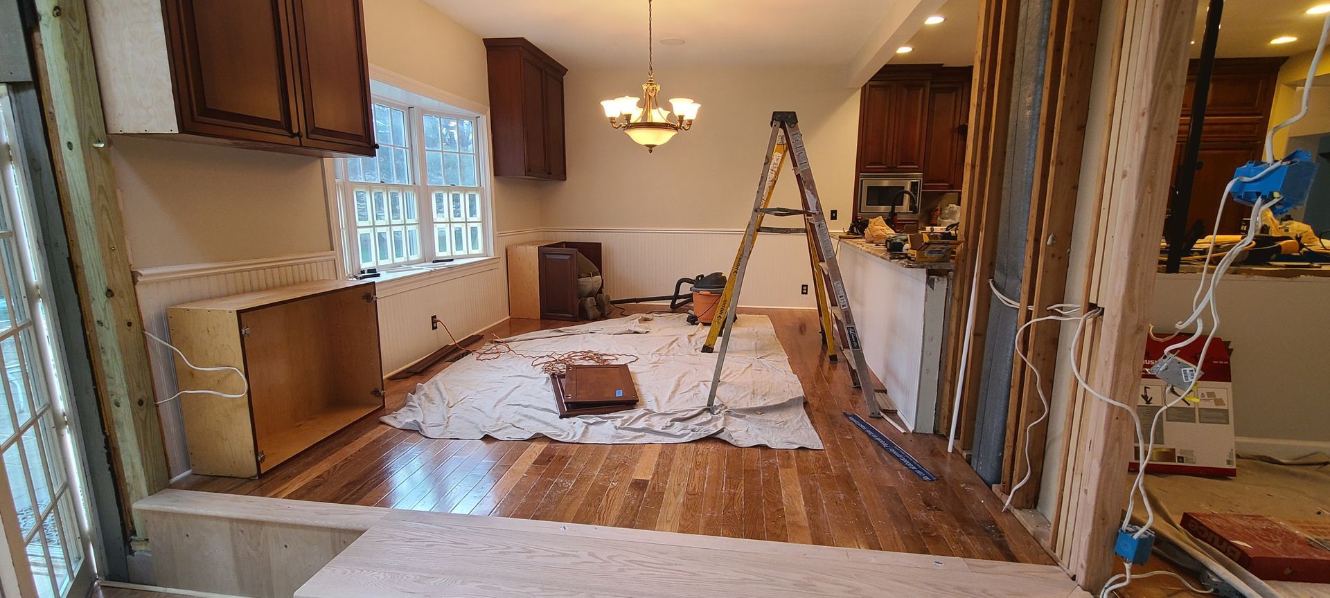 A kitchen is being remodeled with a ladder in the middle of the room.