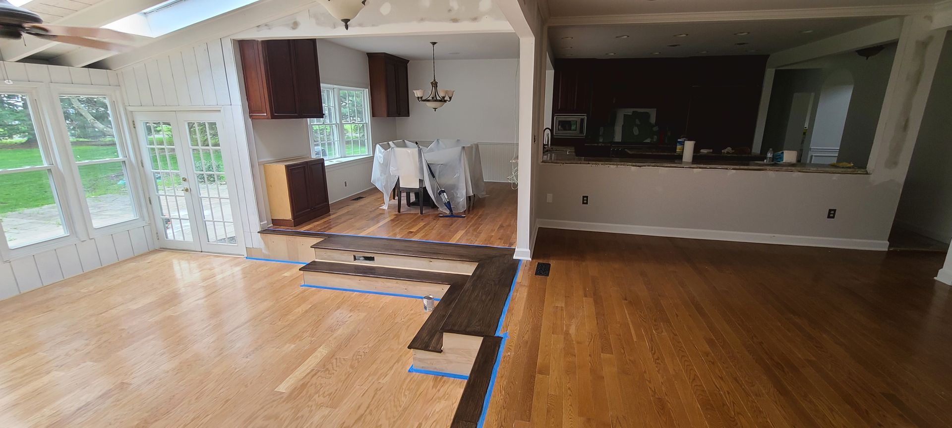A living room with hardwood floors and a kitchen in the background.