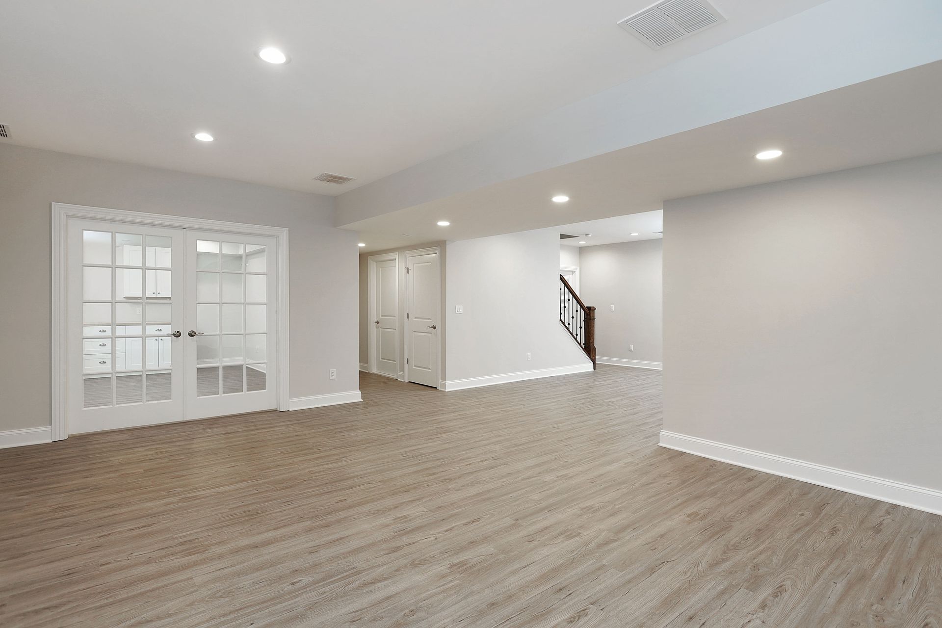 An empty basement with hardwood floors and white walls.