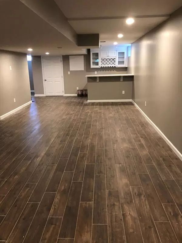 A basement with a wooden floor and gray walls.