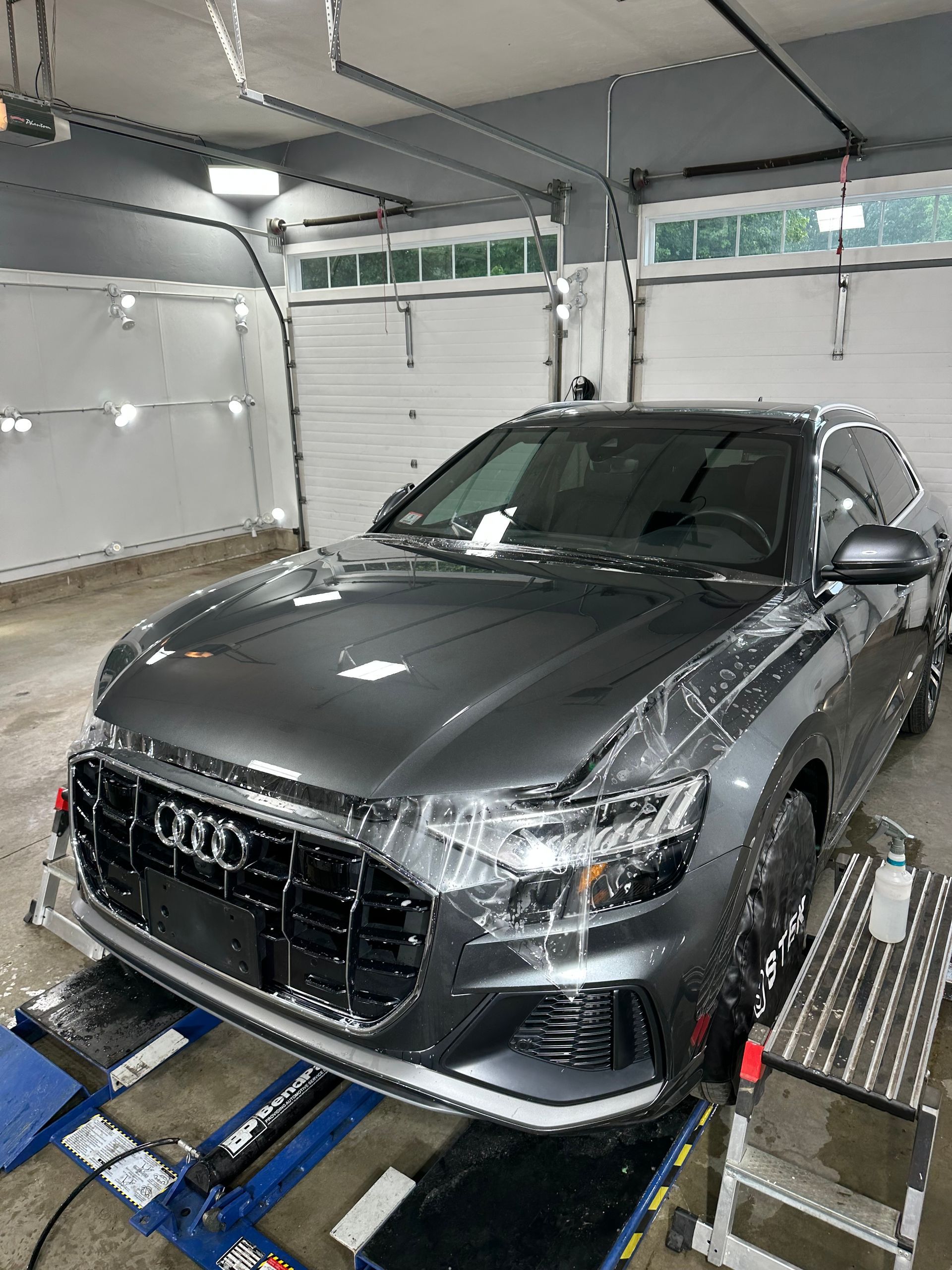 A gray audi q7 is sitting on a lift in a garage.