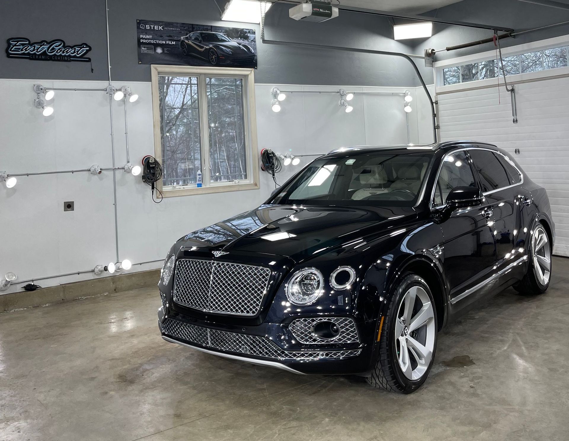 A black bentley is parked in a garage.