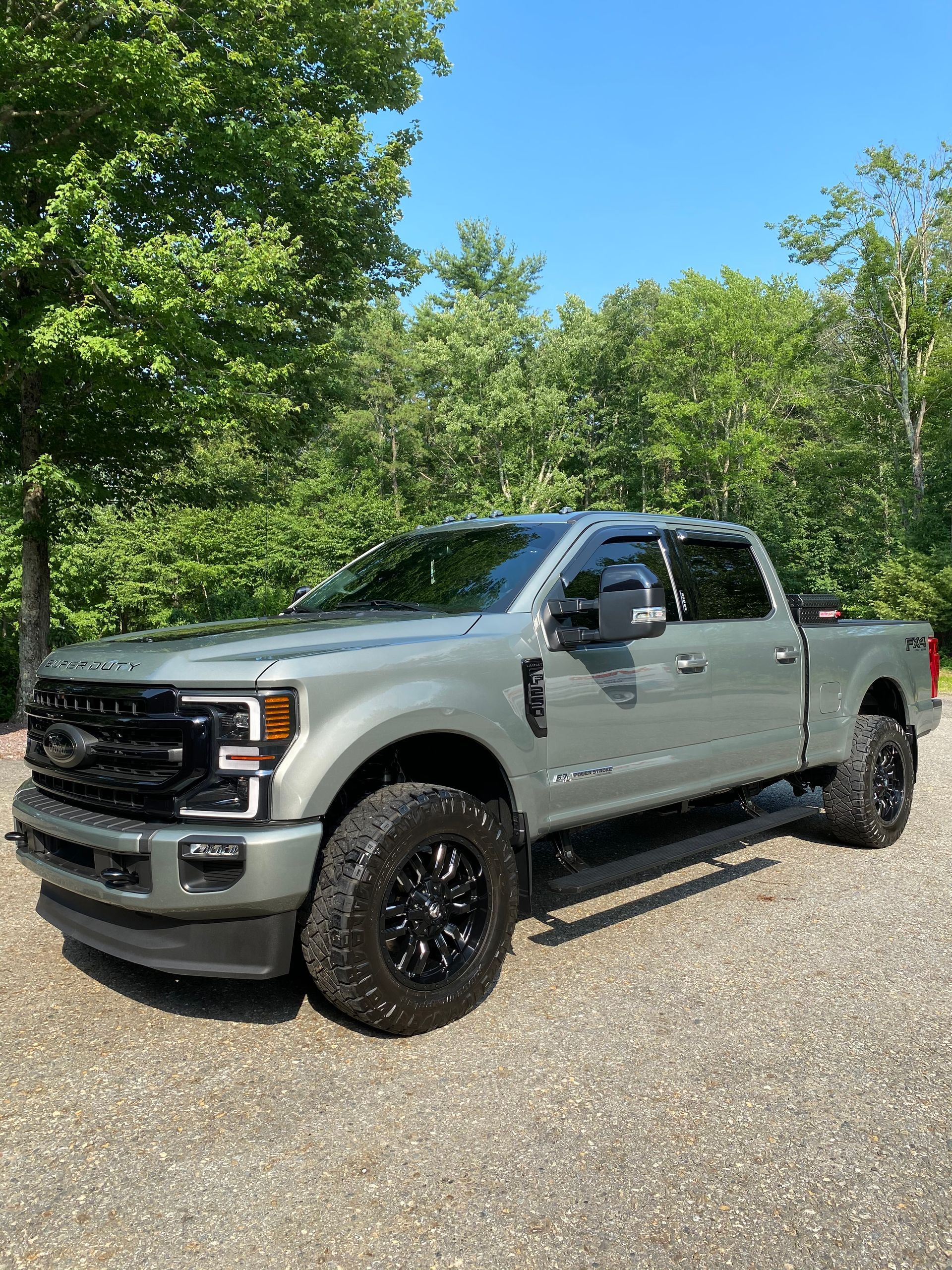 A gray ford truck is parked on a gravel road.