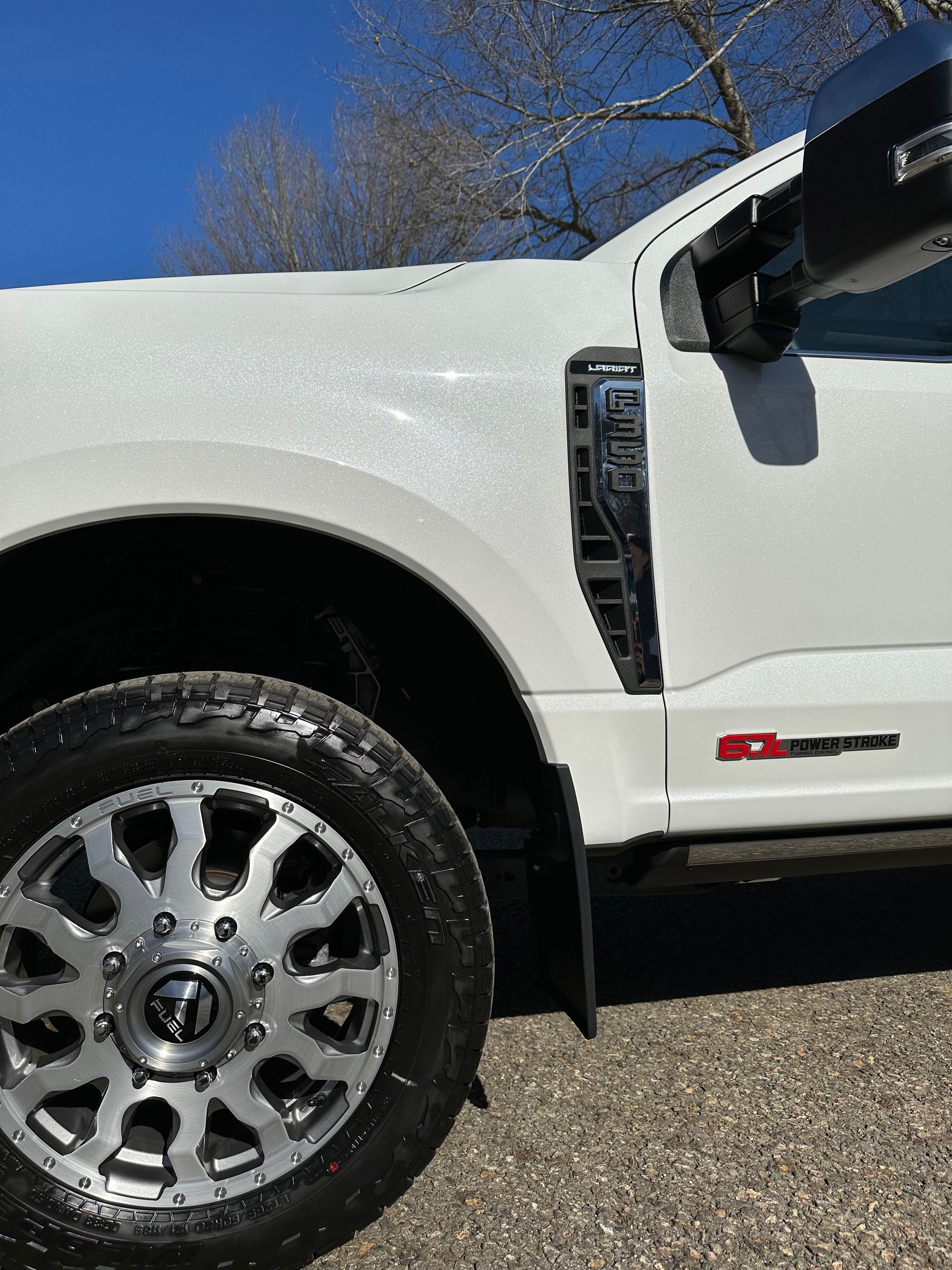 A white truck is parked on a gravel road