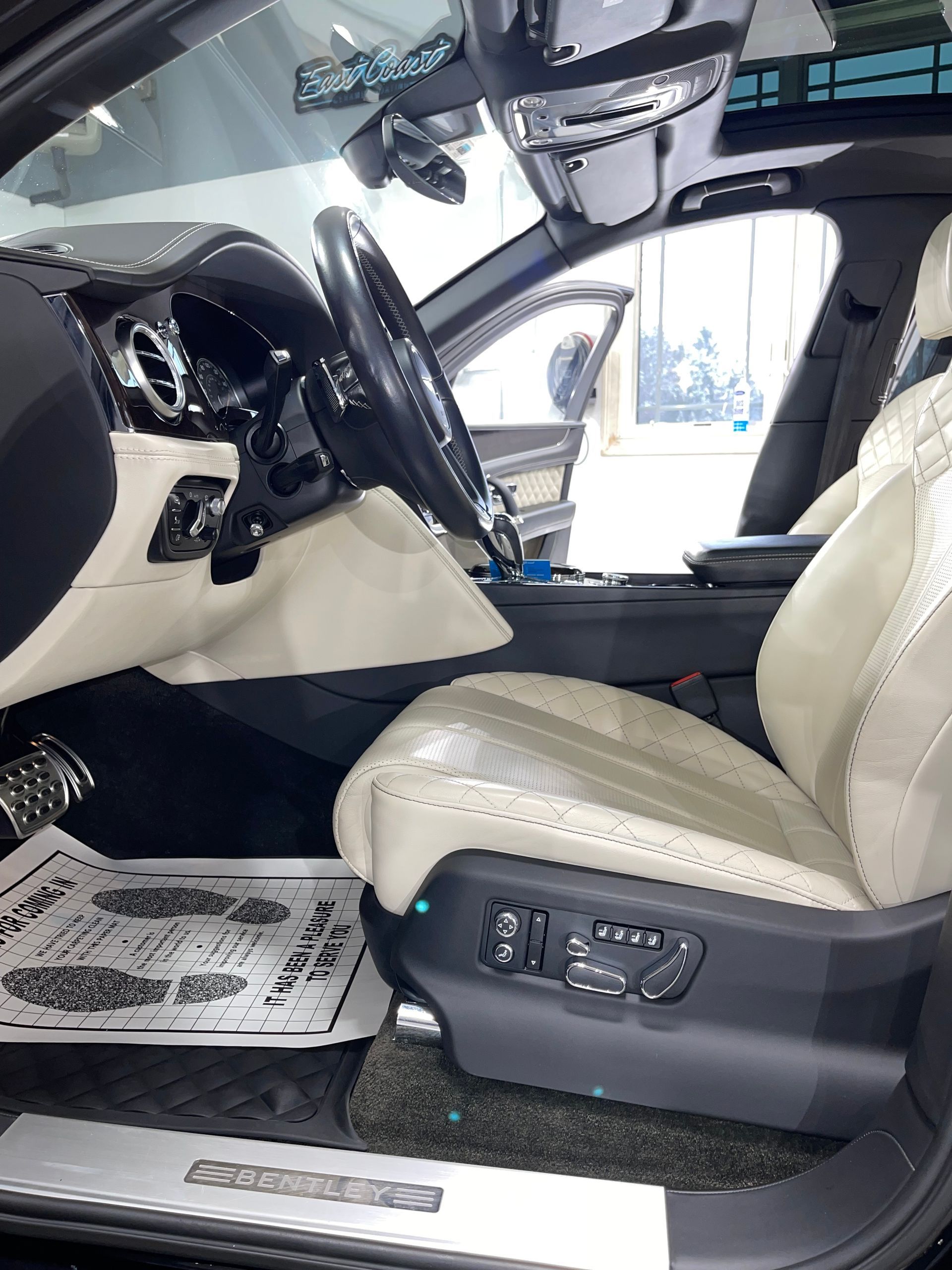 The interior of a black car with white seats and a steering wheel.