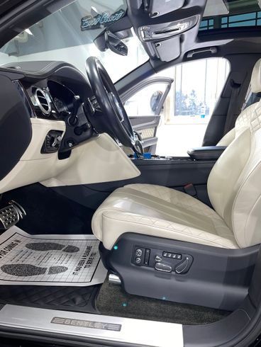 The interior of a black car with white seats and a steering wheel.