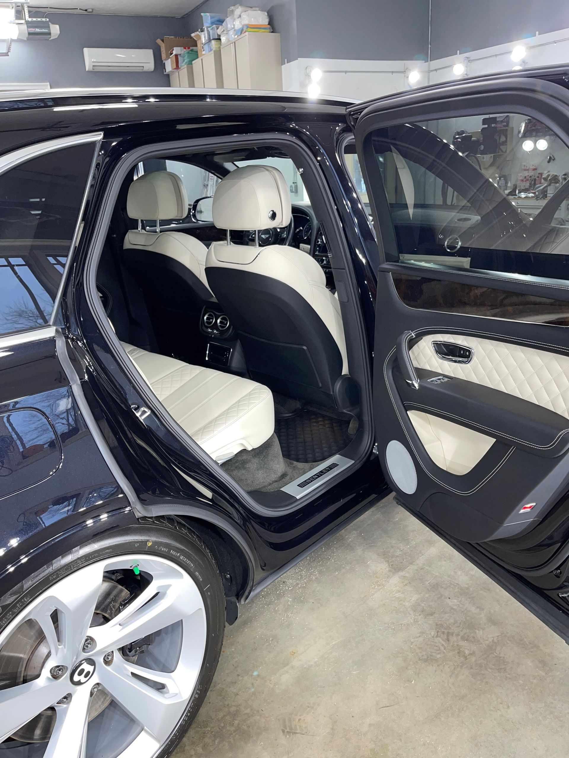 The back seat of a bentley is shown with the door open.