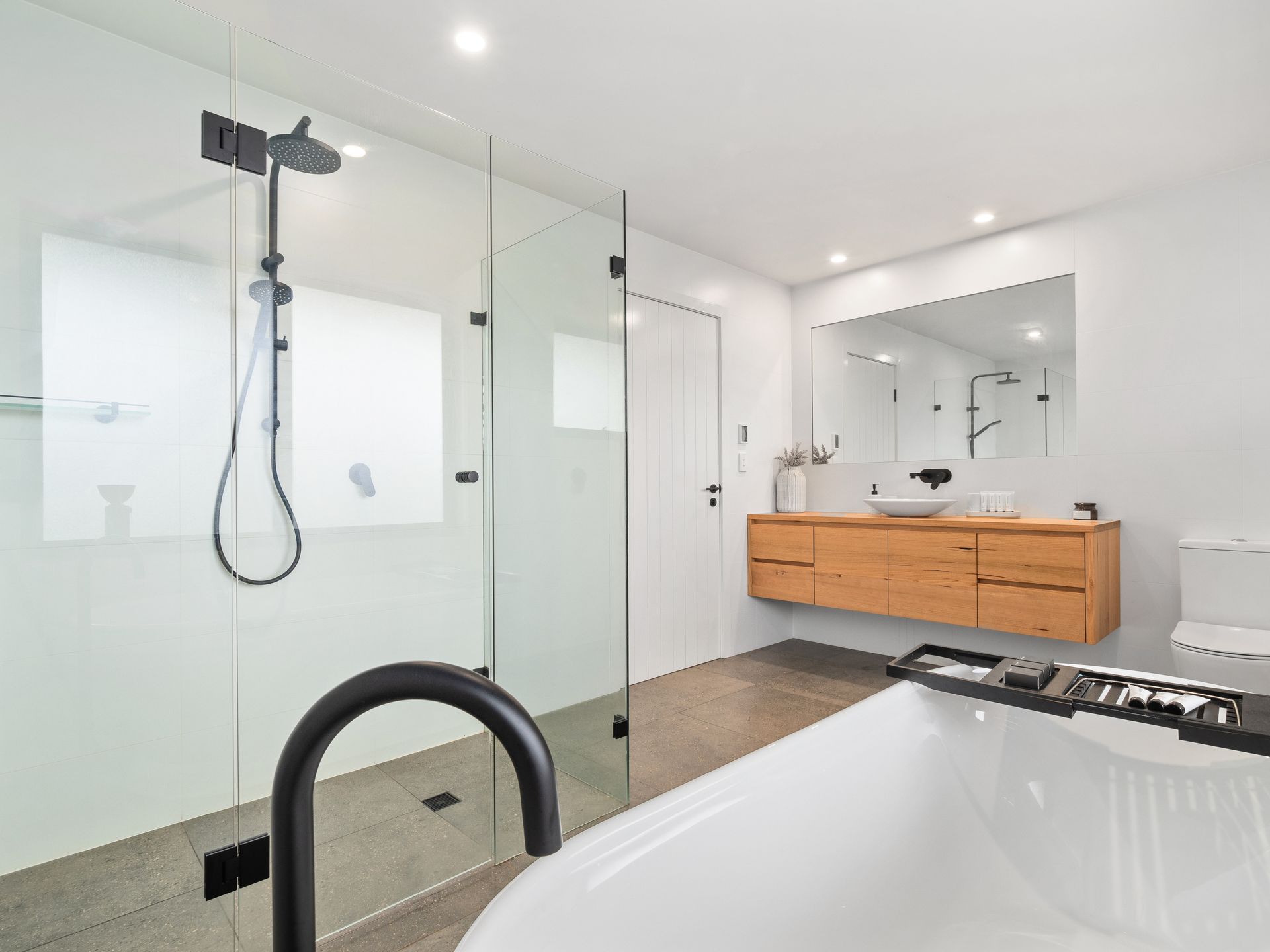 A bathroom with two sinks , a tub and a mirror.