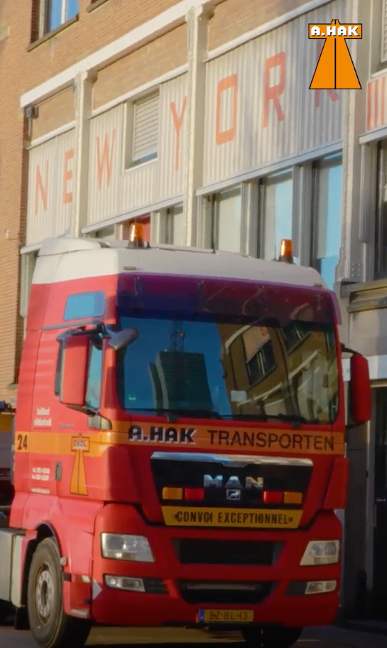 Een rode vrachtwagen staat geparkeerd voor een gebouw met de tekst New York