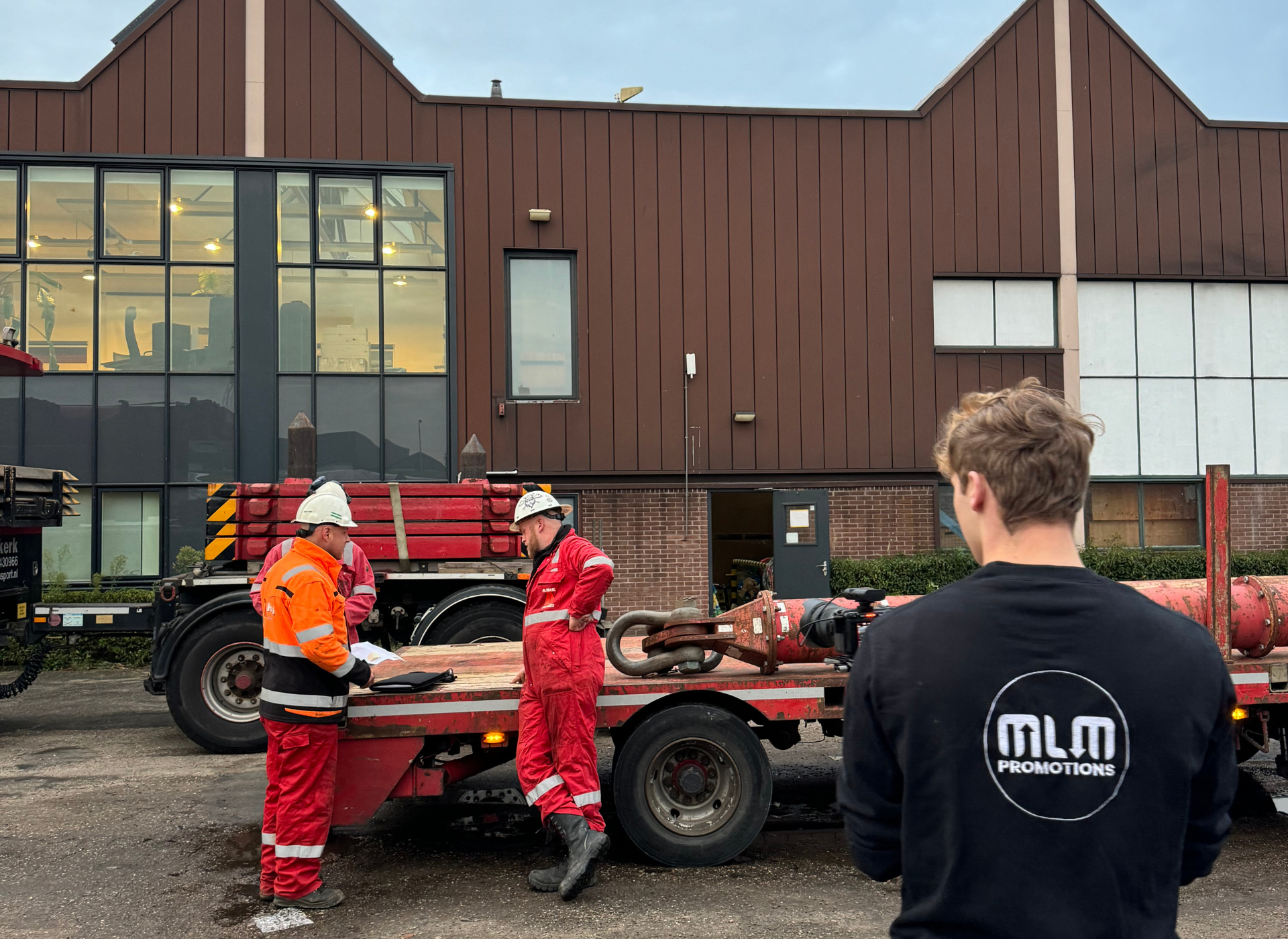 Een man staat voor een gebouw met een MLM-logo op zijn rug.
