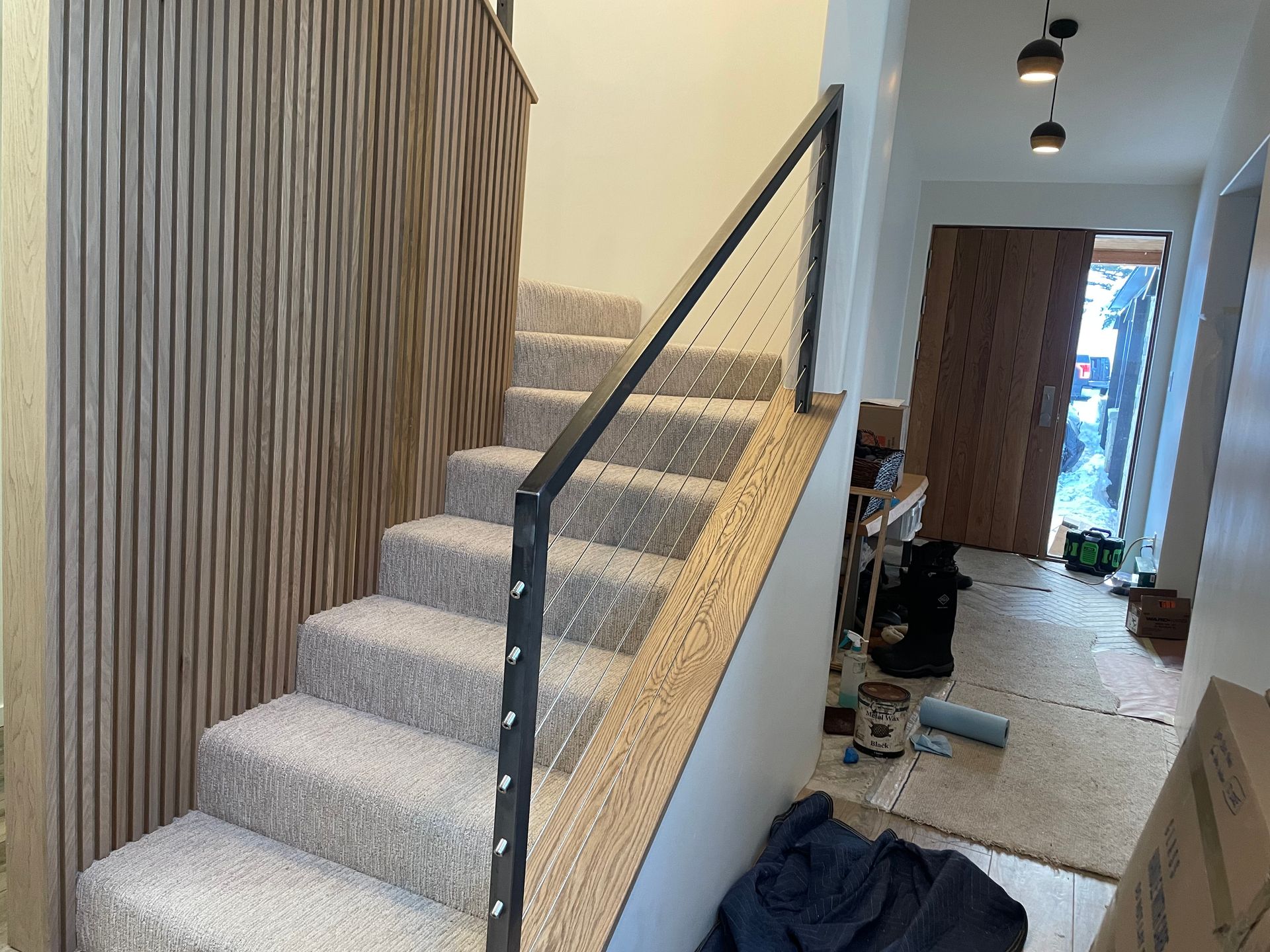 A staircase with carpeted steps and a metal railing in a house.