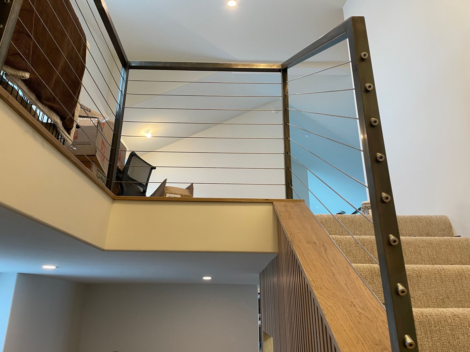 A staircase with a metal railing and a wooden handrail in a house.