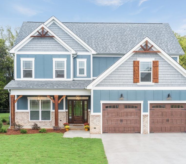 A blue and gray house with two garage doors