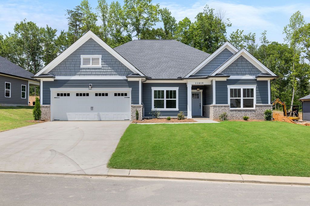 A large blue house with a gray garage door is sitting on top of a lush green lawn.