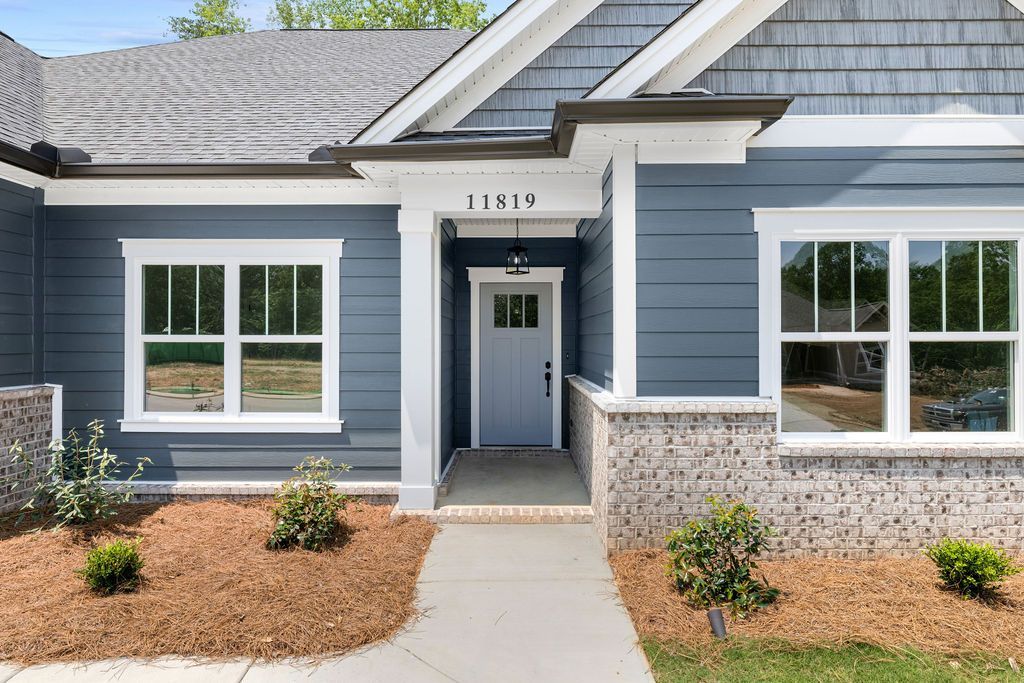 The front of a blue house with white trim and windows.