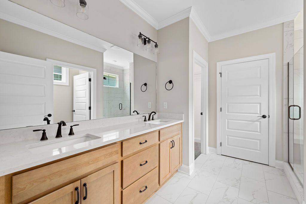 A bathroom with two sinks , two mirrors and a walk in shower.