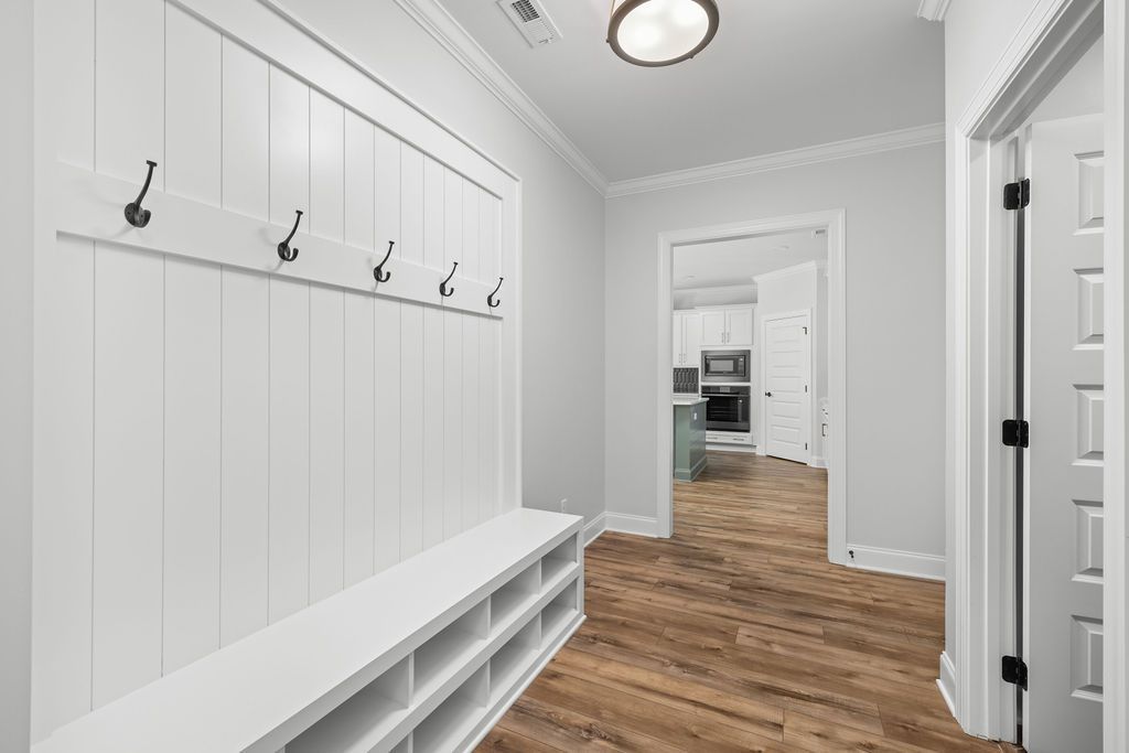 A hallway with a bench and hooks on the wall.