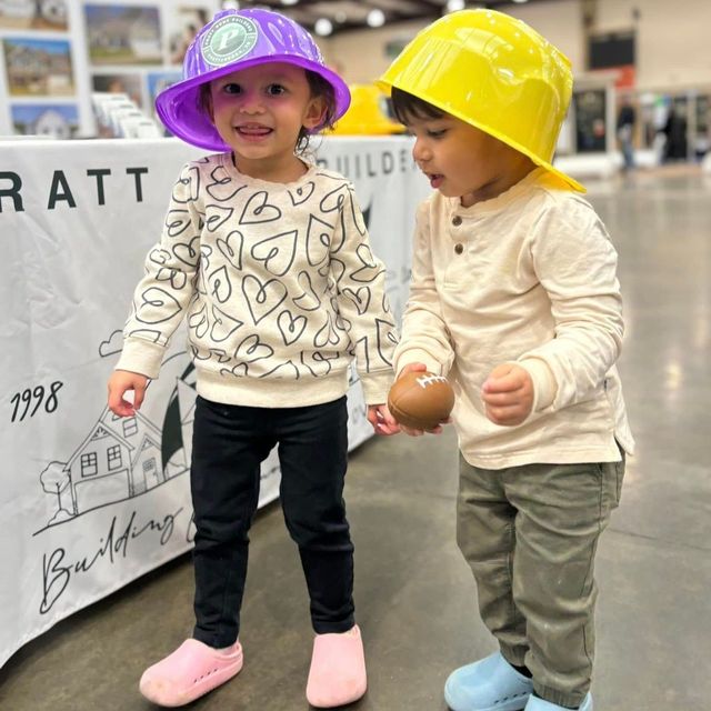 Two children wearing hard hats are standing next to each other
