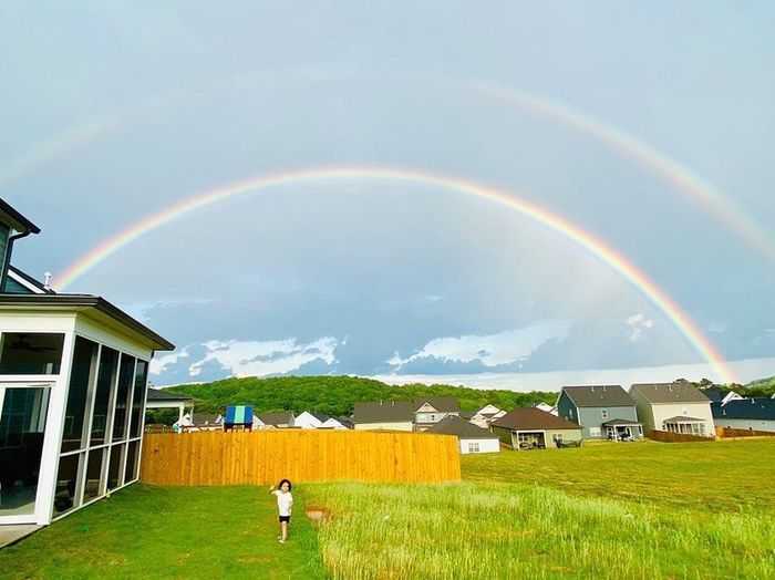 A house with a screened in porch and a rainbow in the sky