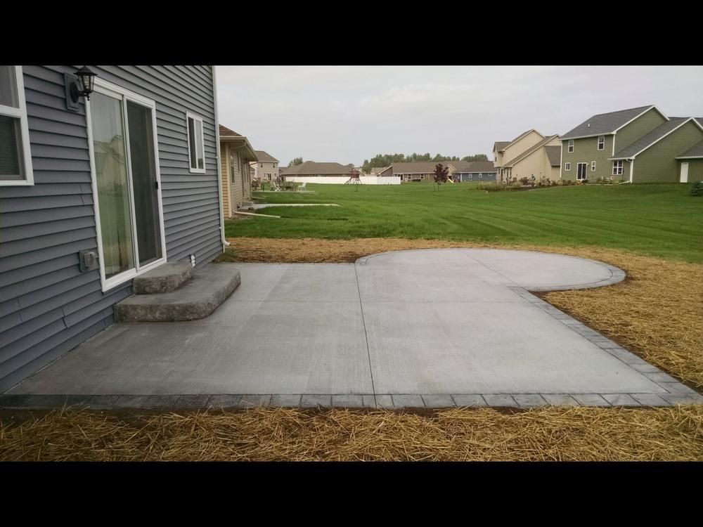 A concrete patio in front of a house with a sliding glass door.