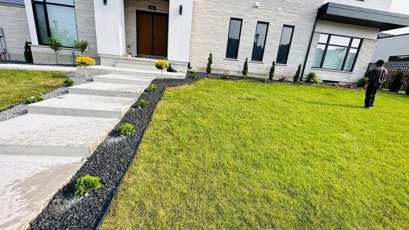 A man is standing in front of a house with a lush green lawn.