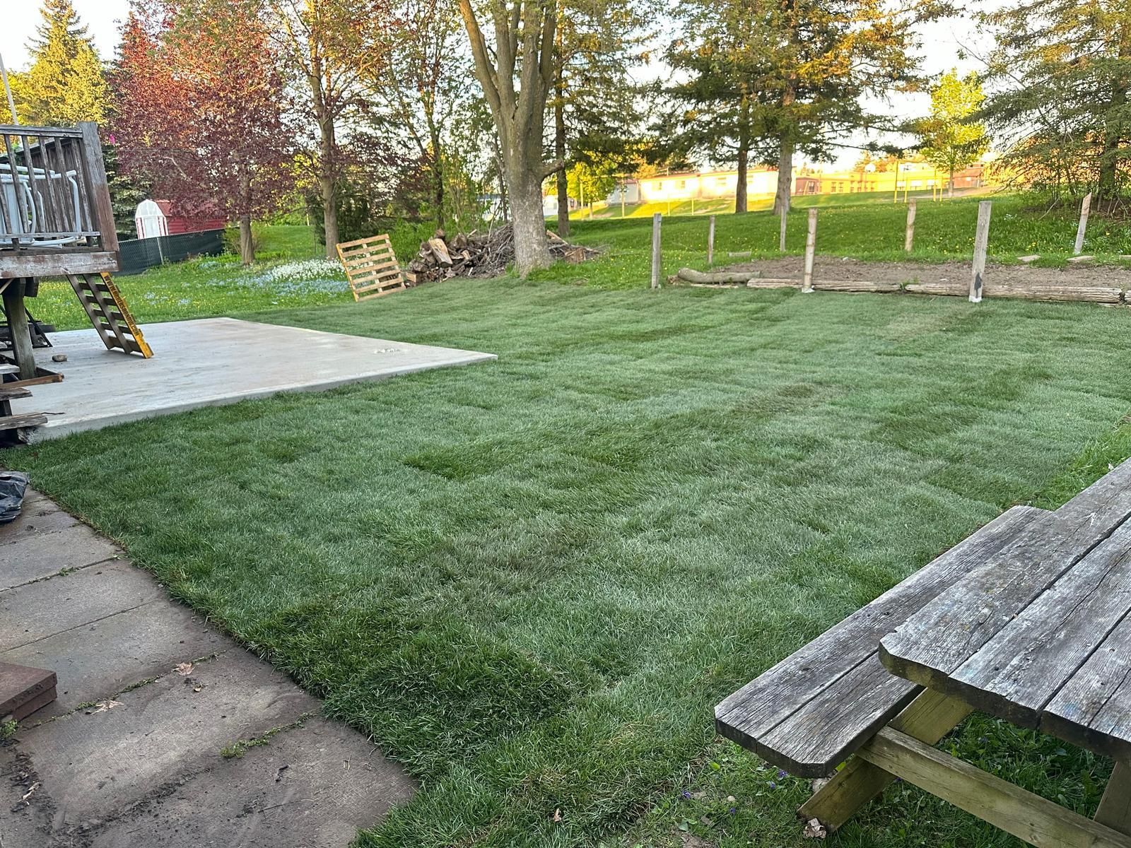 A wooden picnic table is sitting in the middle of a lush green lawn.