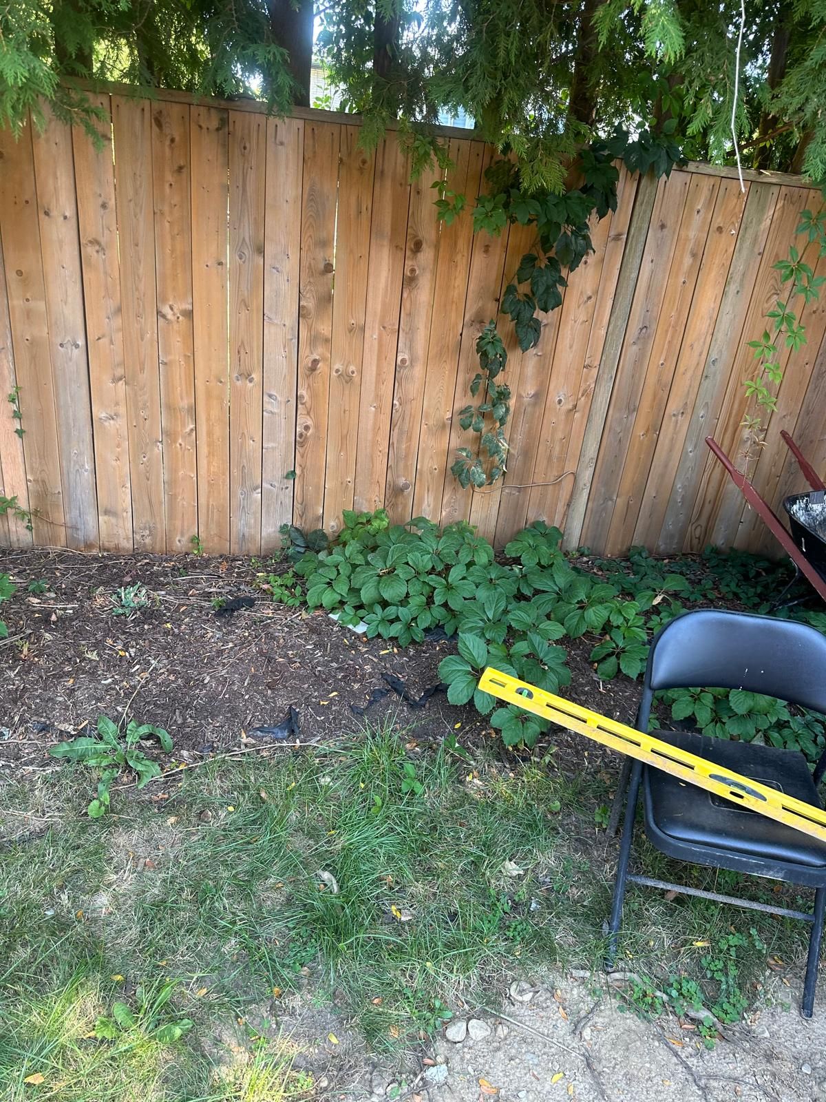 A wooden fence with a chair and a measuring tape in front of it.