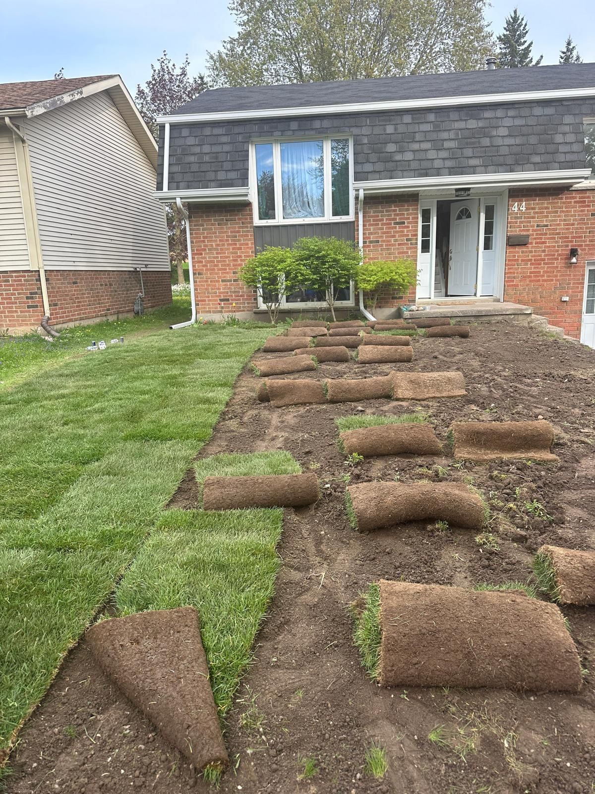 A house with a lot of rolls of grass in front of it.