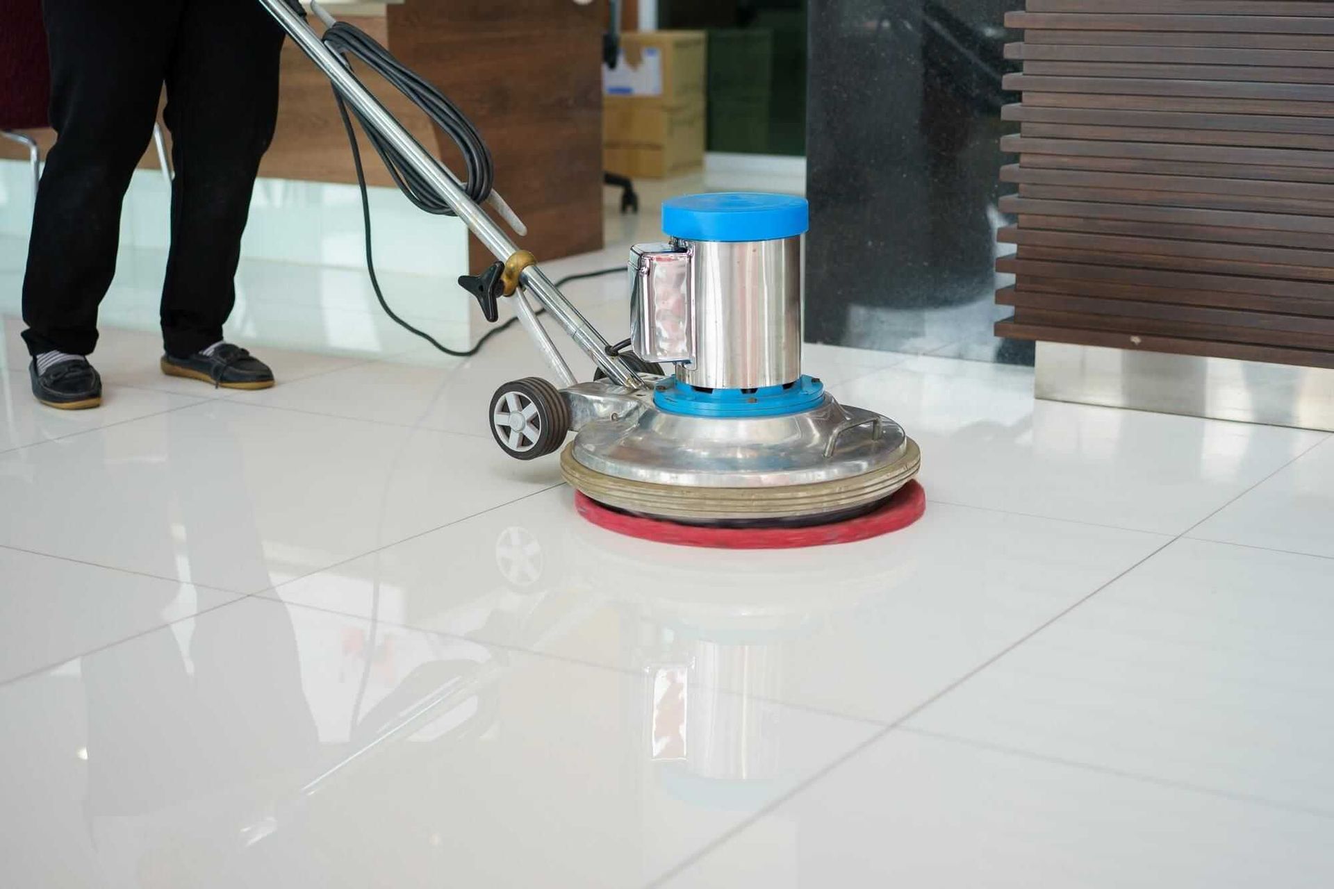 A person is cleaning a tiled floor with a machine.
