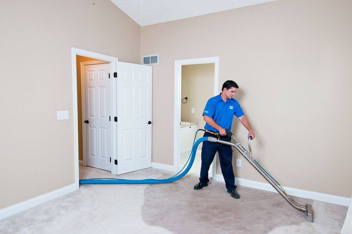 A man is using a vacuum cleaner to clean a carpet in a room.