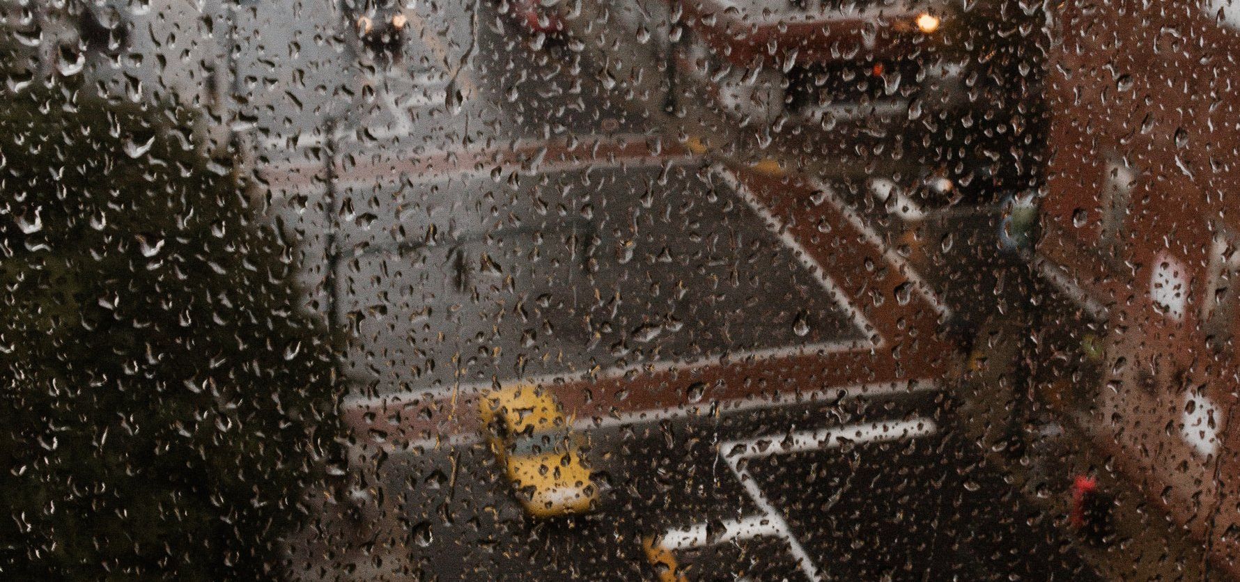 a view of a city street through a window with rain drops on it