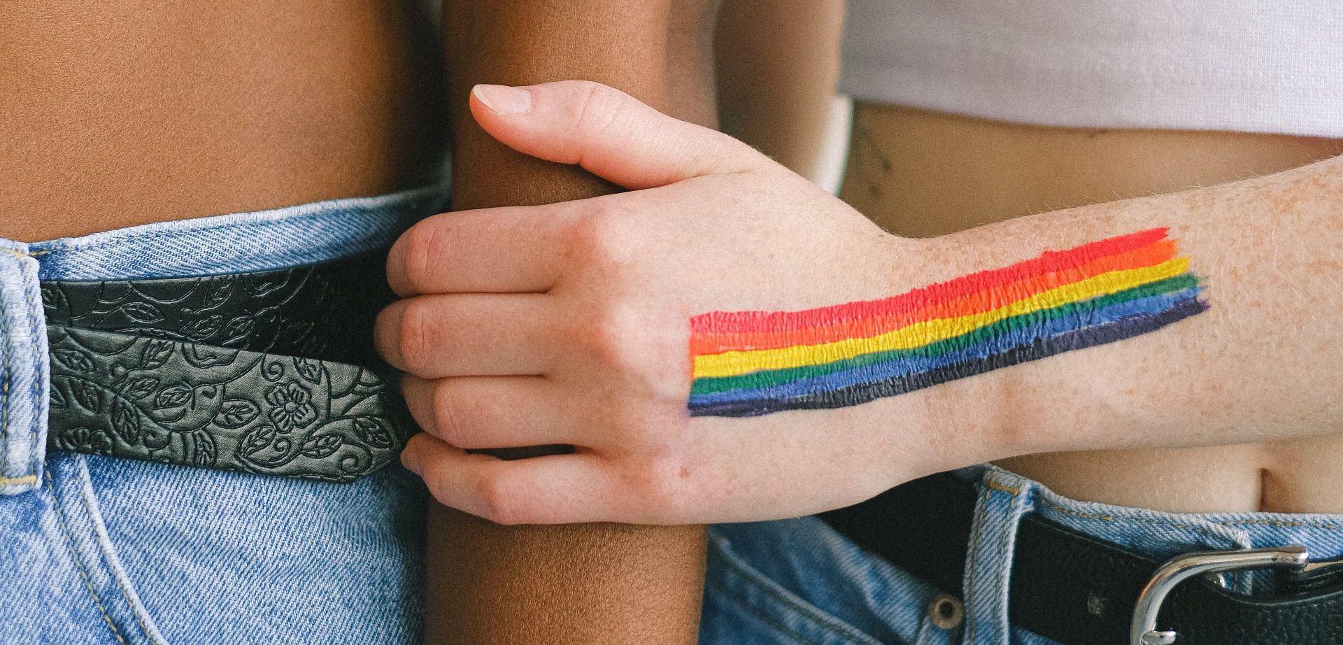 a person with a rainbow tattoo on their wrist.