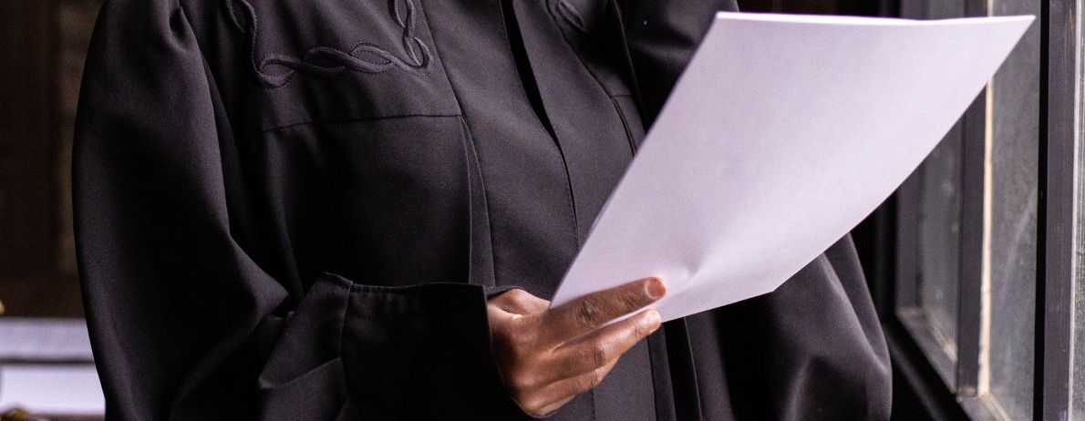 a judge in a black robe is holding a piece of paper in his hands .