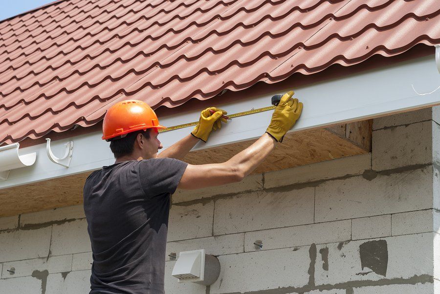 male worker measuring the roof edge of gutter installation