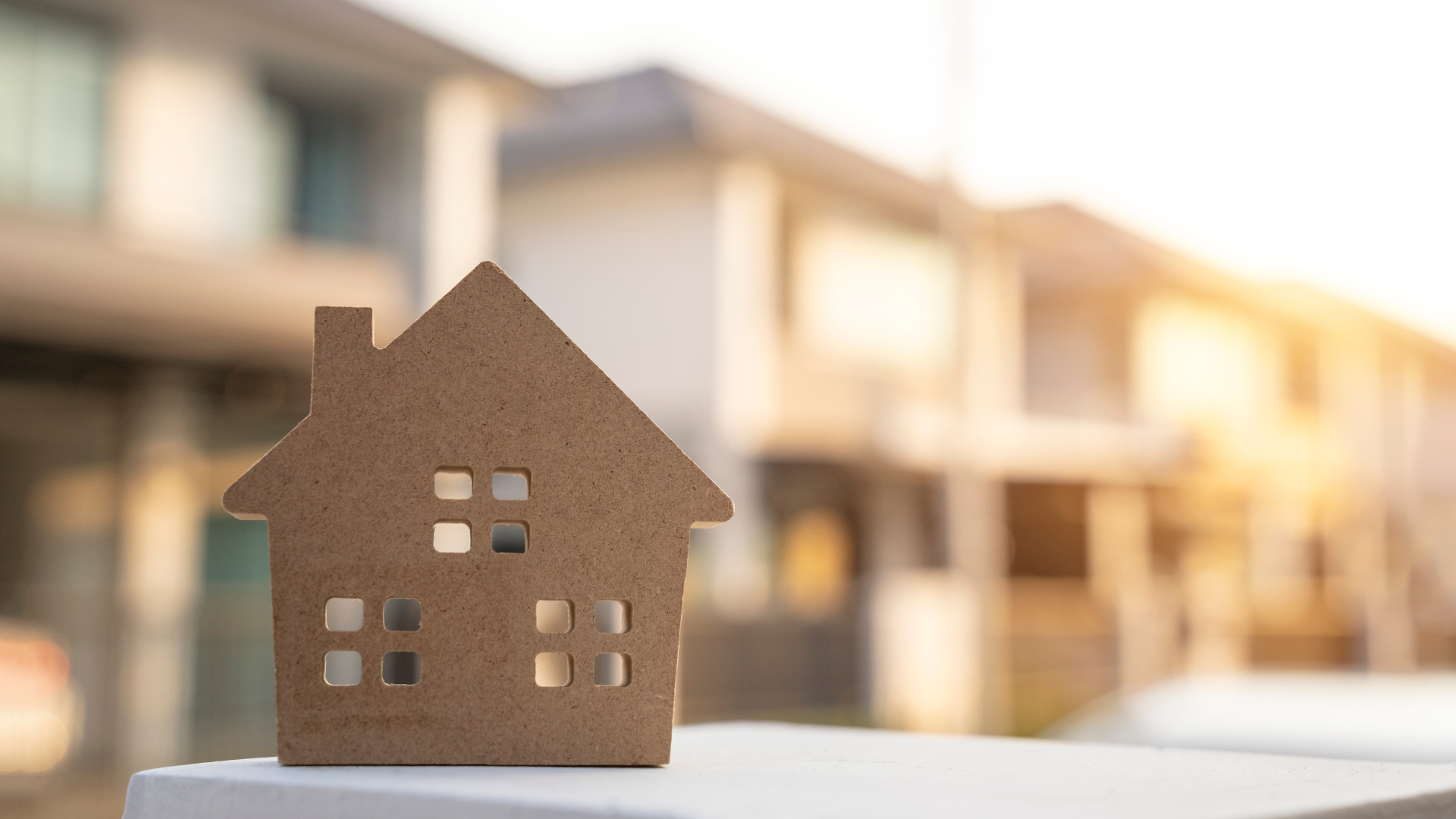 A model house is sitting on top of a pile of money.