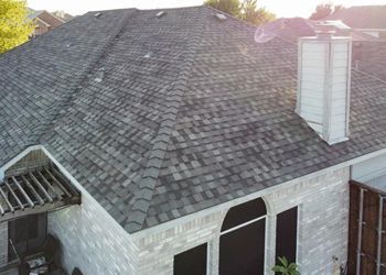 An aerial view of a house with a gray roof and a chimney.