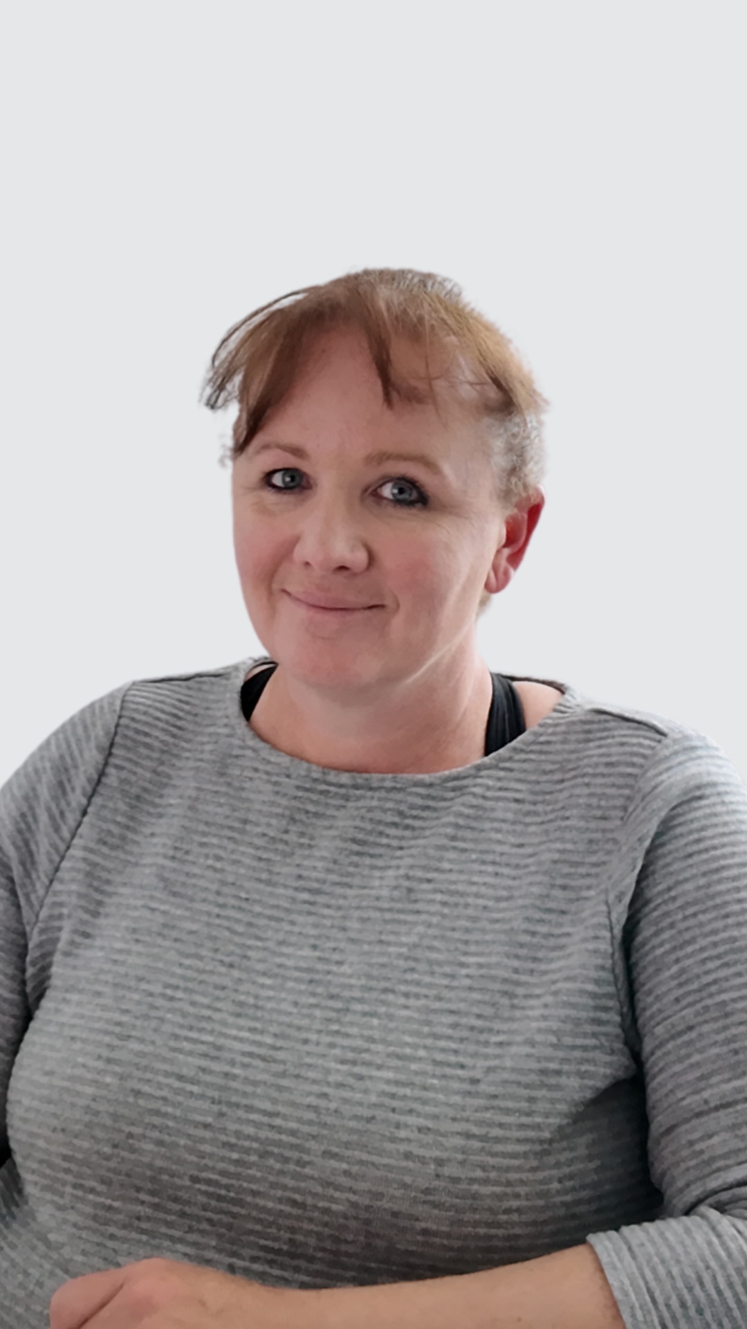 A woman in a grey sweater is smiling for the camera.