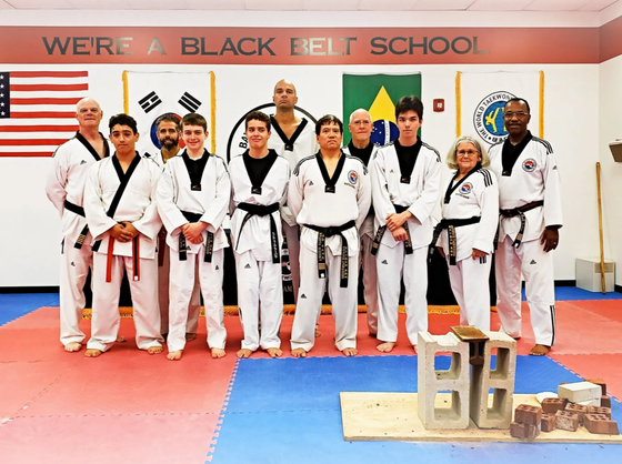 A man in a white karate uniform is holding a black belt