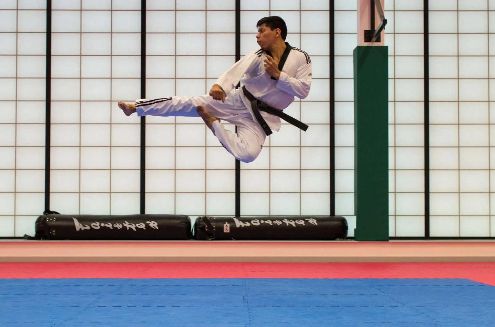 A man in a karate uniform is jumping in the air
