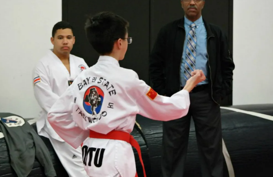 A young boy in a taekwondo uniform with the word baystate on the back