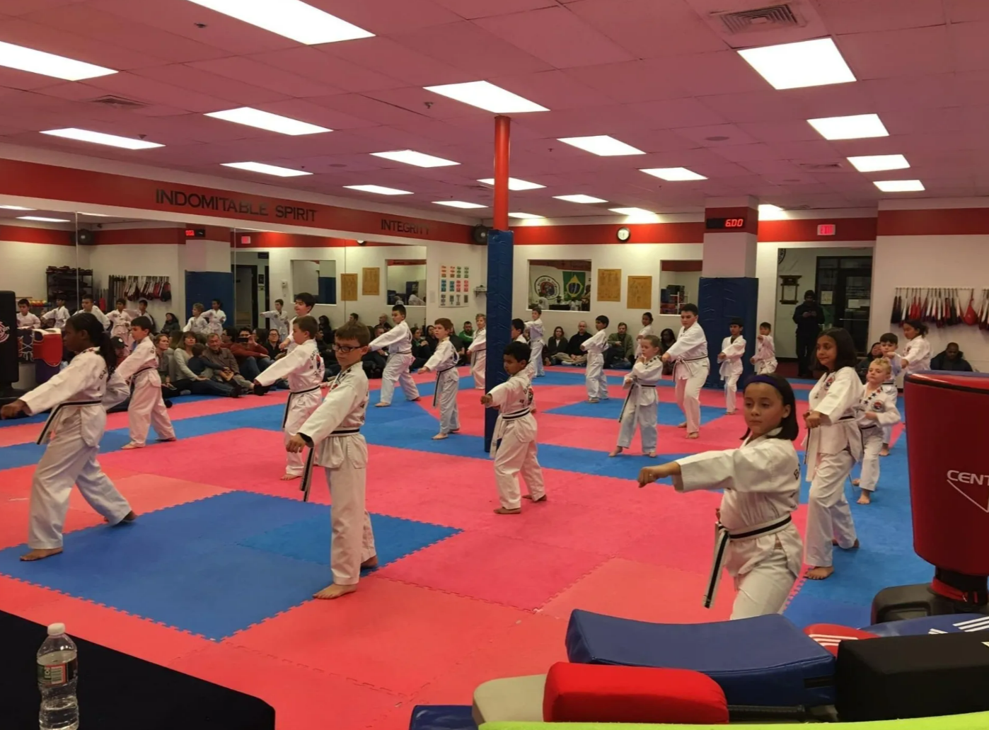 A group of children are practicing martial arts in a gym.